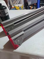 Collapsed Craftsman aluminum sawhorse ends showing branding and red caps