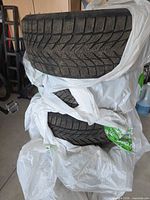 Stacked winter tires in plastic bags showing tread