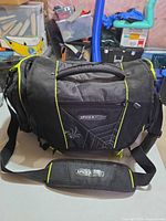 Front view of SpiderWire tackle bag showing logo, neon trim, shoulder strap