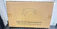 Front of sealed box showing bamboo bed tray table illustration and product text