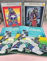 Front view of two 513-piece Indigenous Collection puzzles and two Paint by Stickers books