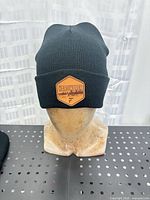 Front view showing Hardwater logo patch on black rib-knit toque