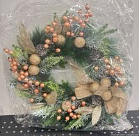 Full view of sealed artificial wreath showing green foliage, gold accents and bow