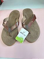Top view of both flip flops showing straps, footbed pattern, hang tag