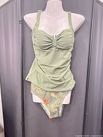 Full view of sage green tankini top on mannequin with bikini bottom displayed