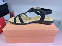 Left side view of sandal on box showing rhinestone straps and low wedge sole