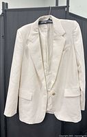 front view of cream blazer on hanger showing overall design