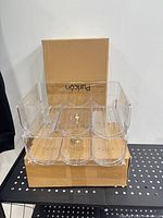 Front view of assembled clear plastic stackable wine bottle holder atop original Puricon box