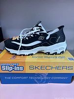 Left side view of one shoe on original box highlighting design and branding