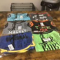 All six packaged shirts laid out showing colors and some slogans
