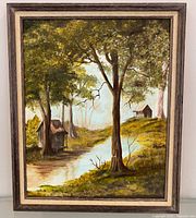 Full view of framed oil painting depicting trees, stream, cabins
