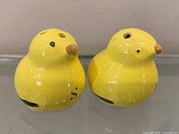 Front view of both yellow ceramic chick shakers showing fill holes and beaks