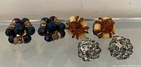 All three pairs of clip-on earrings displayed on glass shelf