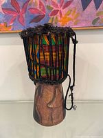 Full view of djembe showing carved wood base and Kente cloth patterned body
