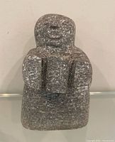 front view of grey soapstone Inuit figure holding object