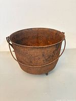 Side view of cast iron pot showing bail handle and tripod legs