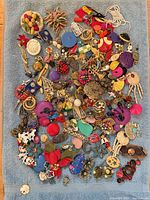Full lot of assorted single earrings spread on blue towel