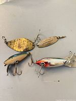Overview of four lures on table: two metal spoons, two hard-body crankbaits
