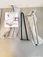 Four hairpin legs, three wrapped in bubble wrap, one unwrapped, with instruction sheet