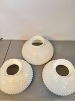 Top view of three white hobnail milk glass shades showing openings