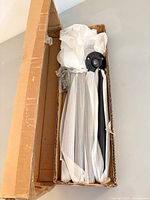Box containing four wrapped black pipe legs, flange and screws visible