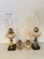 Group shot of all four glass oil lamps with chimneys