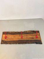 Front view of live edge wood coat rack showing three red hooks