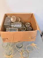 Box containing assorted clear glass jars and metal bands