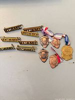 Six brass RCAMC title badges and five copper-tone medals on light surface