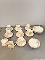 Full set arranged showing mugs, saucers, plates, creamer and sugar bowl