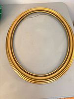 Front view showing gold-tone oval frame and glass