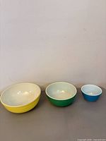 Front view of all three nesting Pyrex bowls colored yellow, green, blue