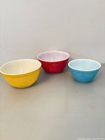 Three Pyrex mixing bowls: yellow, red, blue