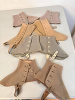 All four pairs of spats laid out on table showing colors and fasteners