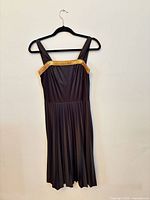 Front view of gray sleeveless pleated dress with gold sequin band