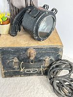 Spotlight resting on wooden case with cable coiled beside