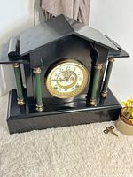 Front view of black iron mantle clock with key nearby