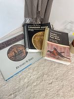 Three reference books laid out: Coins of New Brunswick, Charlton Canadian Coins, Charlton Paper Money