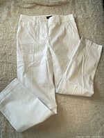 Full view of white chino pants laid flat