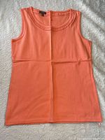 Front view of orange sleeveless top laid flat