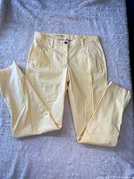 Front view of yellow Talbots girlfriend chino pants laid flat showing pockets, button and zip closure