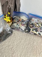Overview of three zipper bags: two filled with mixed buttons, one with bobby pins