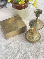 Group view of brass box, enamel candlestick and bell-shaped piece