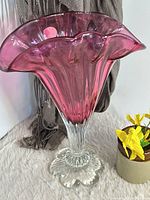 Full view of cranberry glass vase showing ruffled rim and clear stem