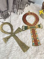 Front view of both brass ankhs on fabric surface