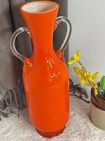 Full view of bright orange glass vase with double clear handles