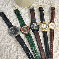 Five watches laid out showing dial variety and leather straps
