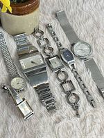 Six stainless steel wristwatches laid out on fabric