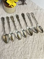 Full set of seven sterling spoons on fabric surface