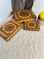 three graduated carved wooden boxes closed showing top design